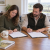 Two UK dog owners reviewing and signing a written breeding agreement before mating